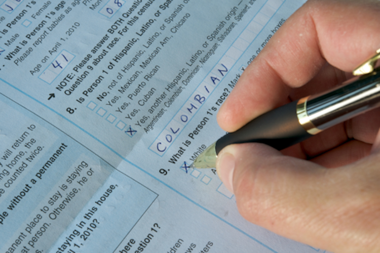 A person's hand documents their Hispanic ethnicity on a census form. 